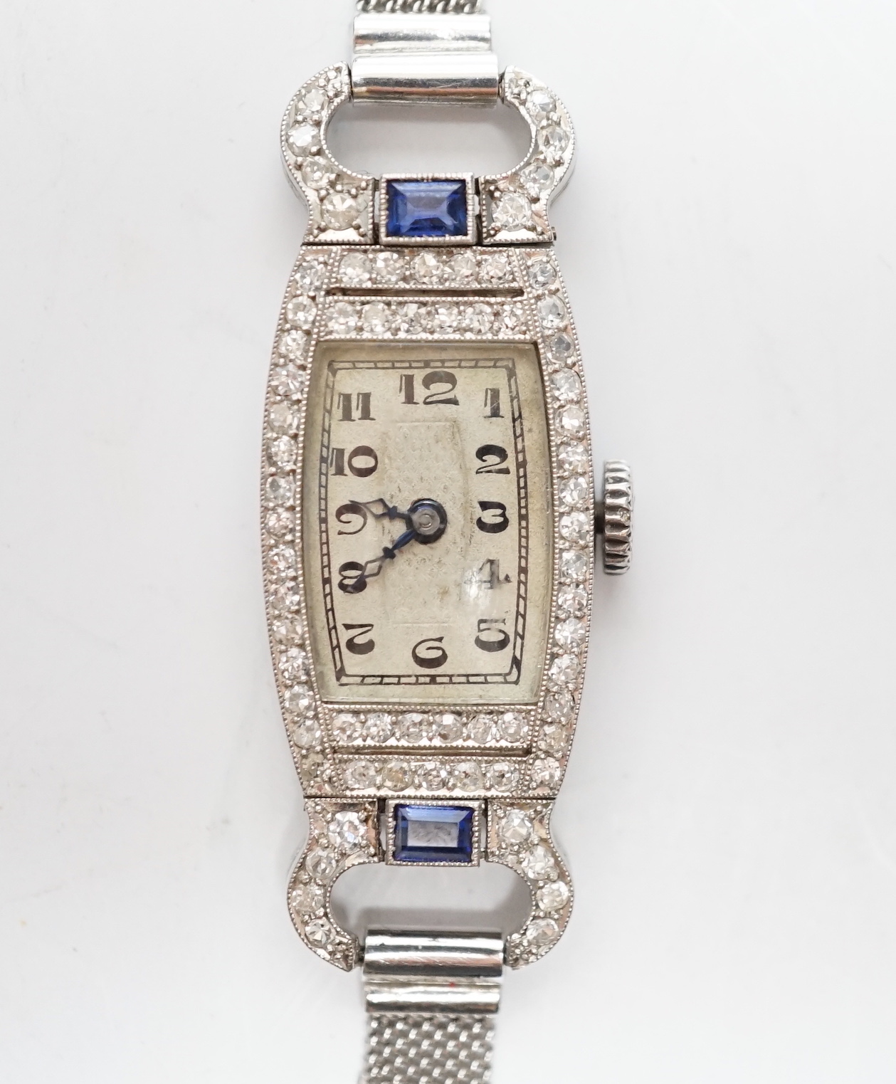 A lady's mid 20th century white metal (Swiss platinum mark), sapphire and diamond cluster set manual wind cocktail watch, with Arabic dial, on and adjustable 9ct mesh link bracelet, gross weight 18 grams.